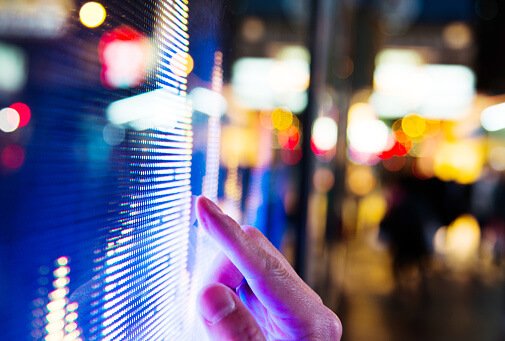 Man Finger Pointing At Led Screen Of Stock Market Price At Night.